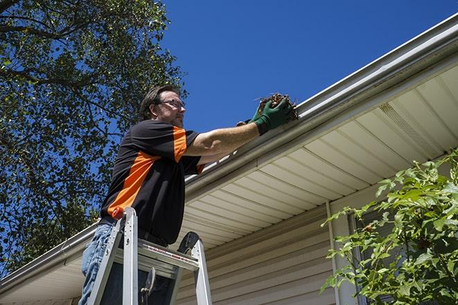 a skilled worker fixing broken gutter on a roof in Malvern IA